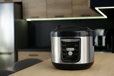 Modern multi cooker on table in kitchen. Space for text