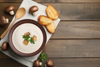 Fresh homemade mushroom soup served on wooden table, flat lay. Space for text