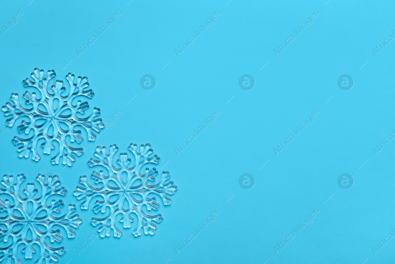 Photo of Beautiful decorative snowflakes on light blue background, flat lay. Space for text