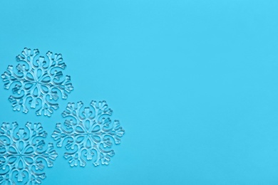 Beautiful decorative snowflakes on light blue background, flat lay. Space for text