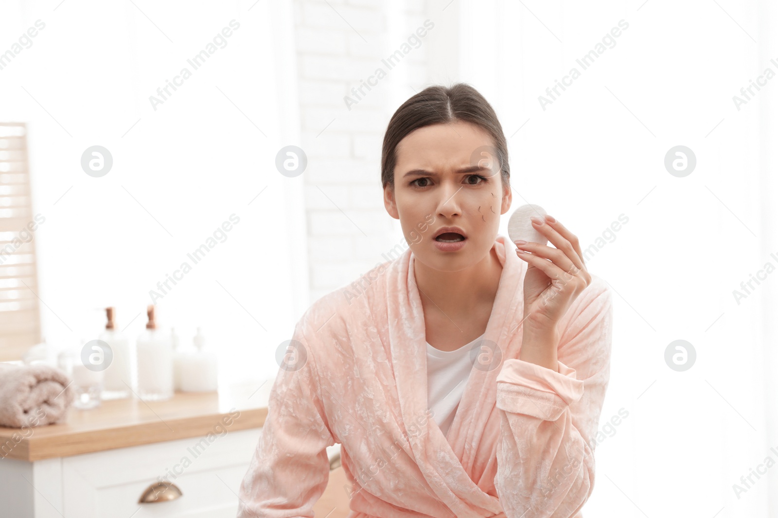 Photo of Beautiful woman with fallen eyelashes holding cotton pad indoors
