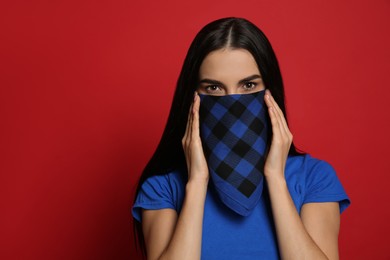 Photo of Young woman with bandana covering her face on red background, space for text