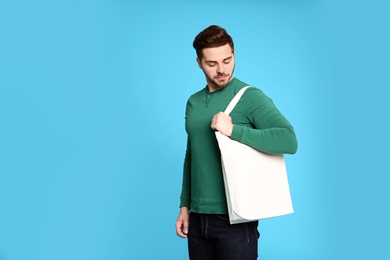 Portrait of young man with eco bag on blue background. Space for text