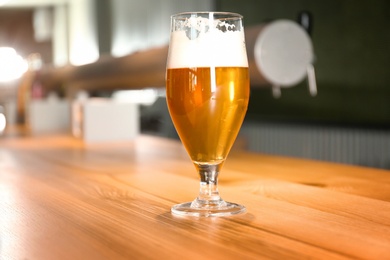 Glass of beer on wooden table in pub