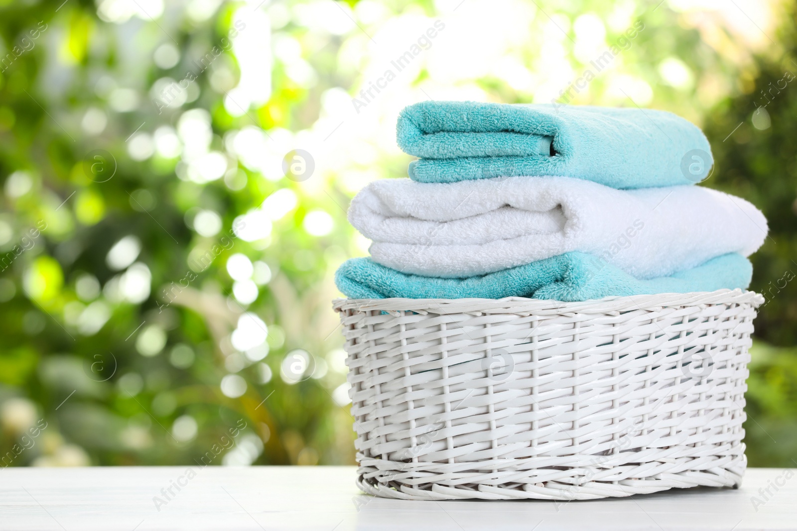 Photo of Basket with soft bath towels on table against blurred background. Space for text