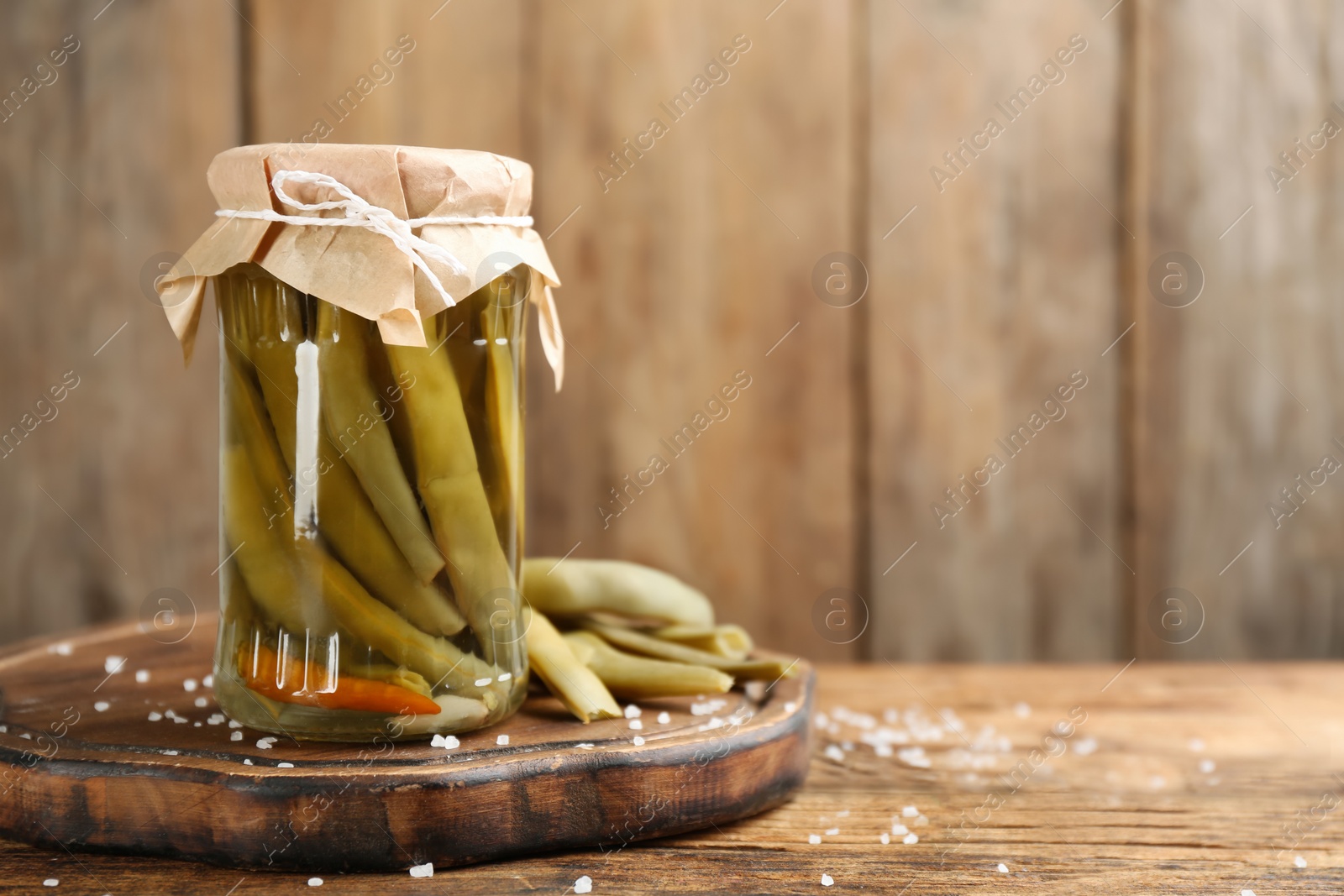 Photo of Canned green beans on wooden table. Space for text