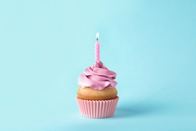 Photo of Delicious birthday cupcake with candle on color background