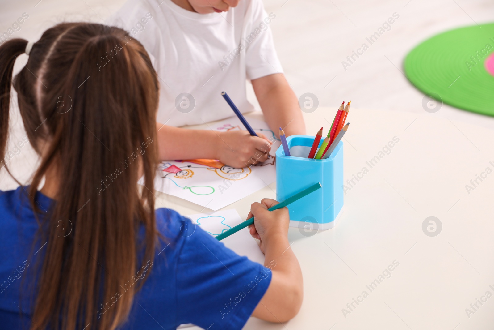 Photo of Little children drawing pictures at desk in kindergarten, closeup