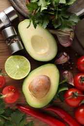 Photo of Fresh ingredients for guacamole on wooden table, flat lay