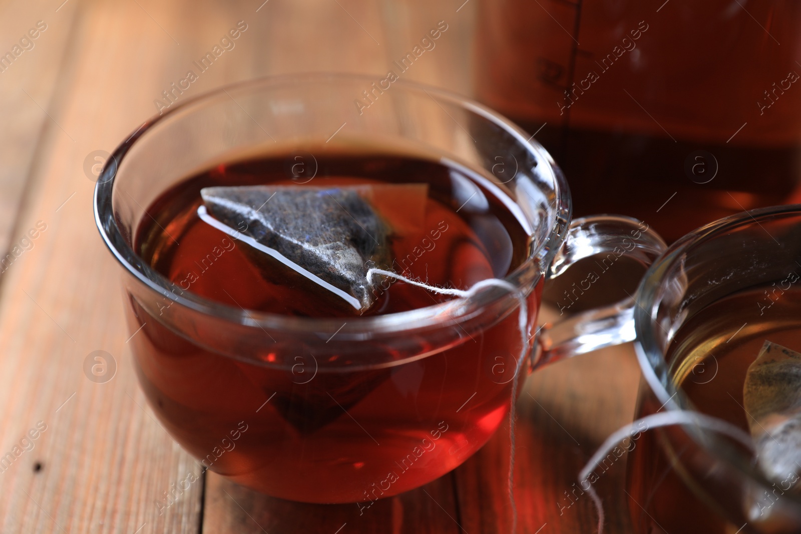 Photo of Tea bag in cup on wooden table, closeup