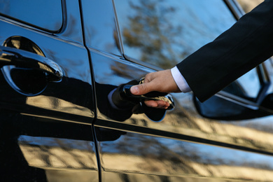 Photo of Driver opening door of luxury car, closeup. Chauffeur service