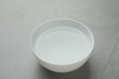Photo of White bowl with water on grey table