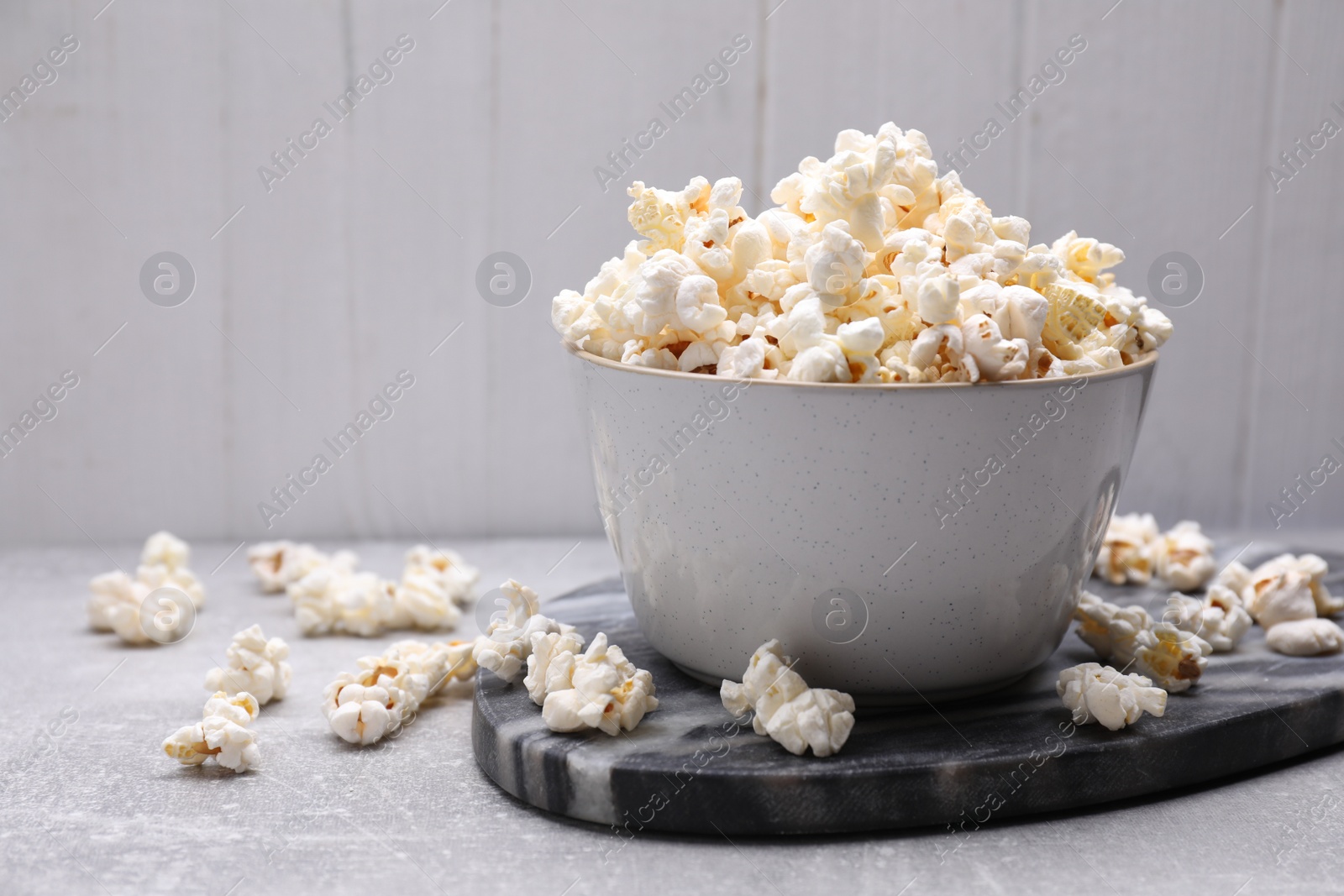 Photo of Bowl of tasty popcorn on grey table, space for text