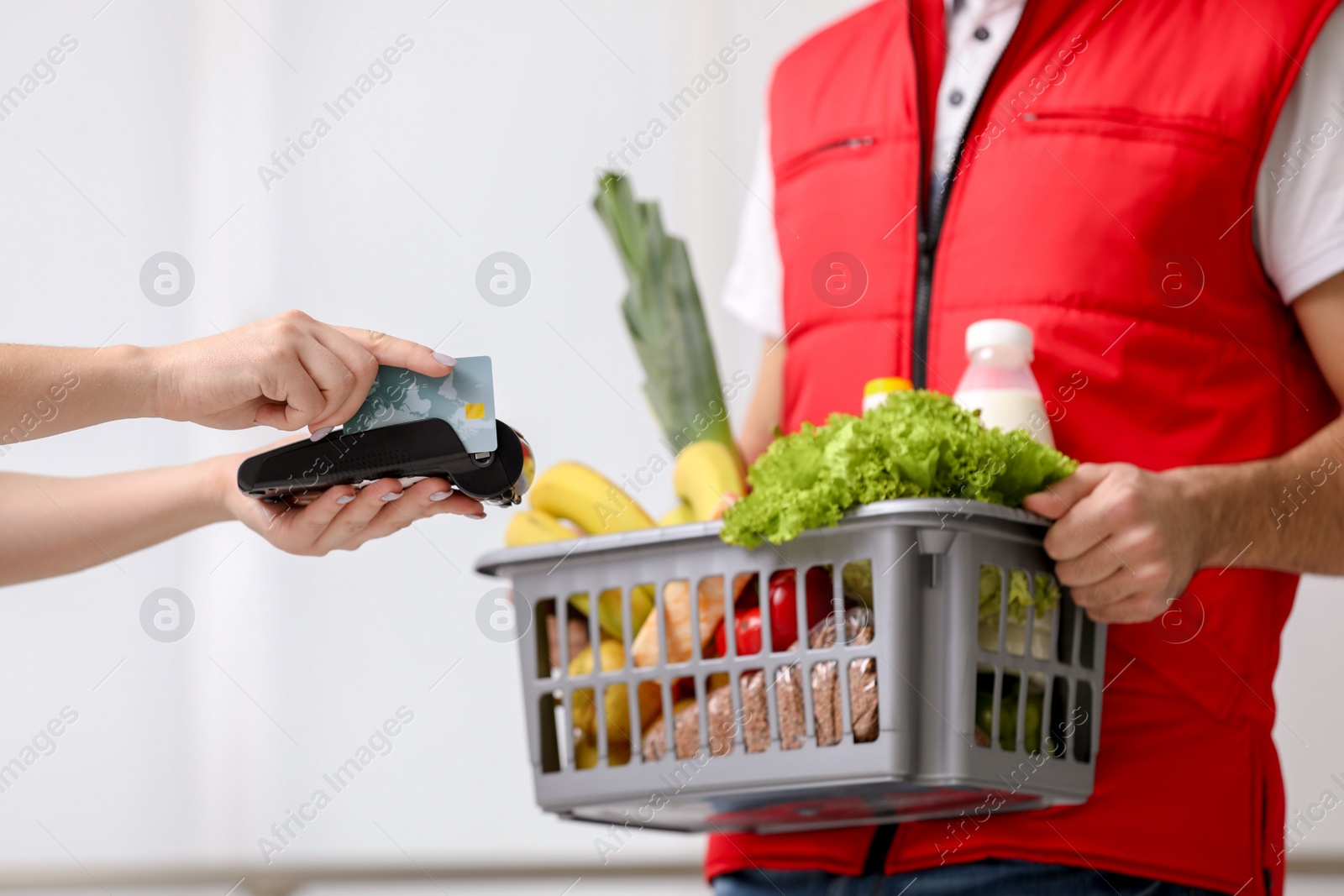 Photo of Customer using bank terminal to pay for food delivery indoors, closeup