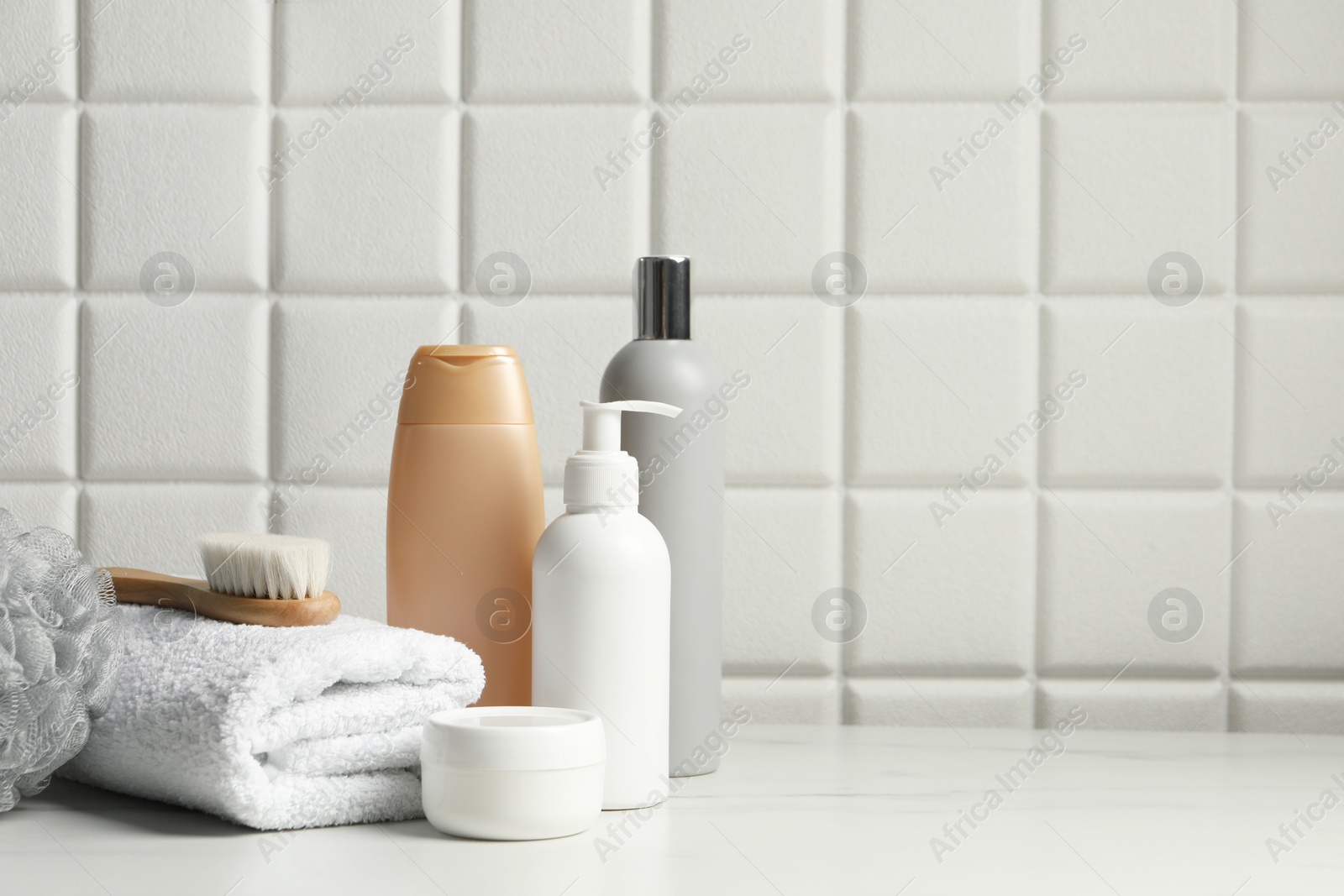 Photo of Different bath accessories and personal care products on white table near tiled wall, space for text