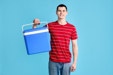 Man with cool box on light blue background