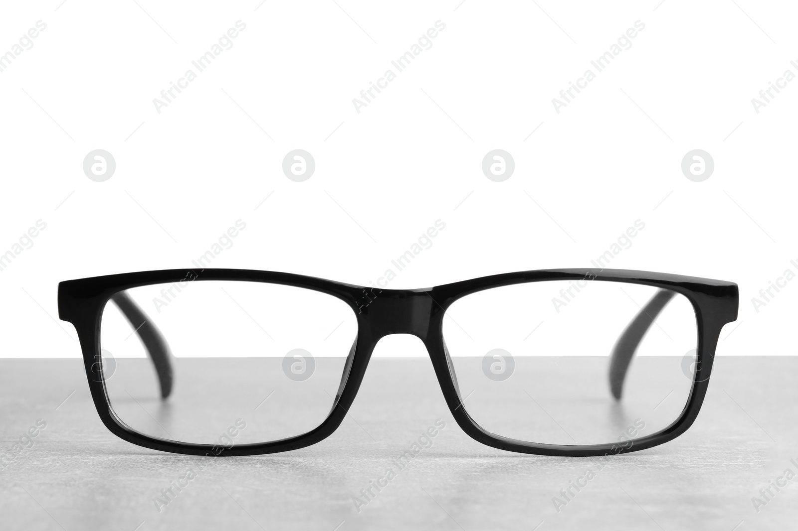 Photo of Stylish glasses with black frame on table against white background