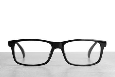 Stylish glasses with black frame on table against white background
