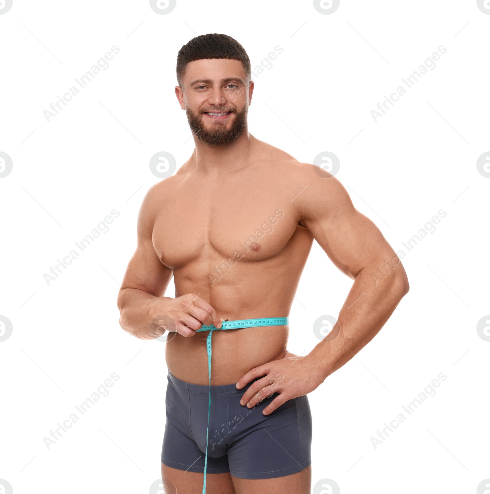 Photo of Portrait of happy athletic man measuring waist with tape on white background. Weight loss concept