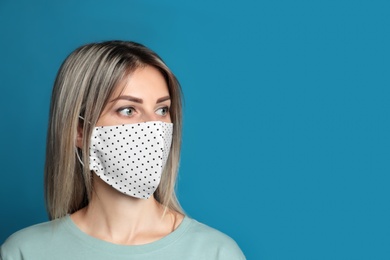 Young woman in protective face mask on blue background. Space for text