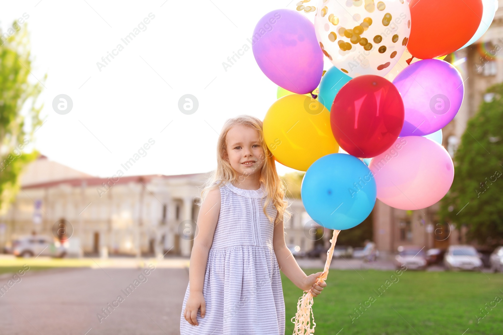 Photo of Cute little girl with colorful balloons outdoors on sunny day