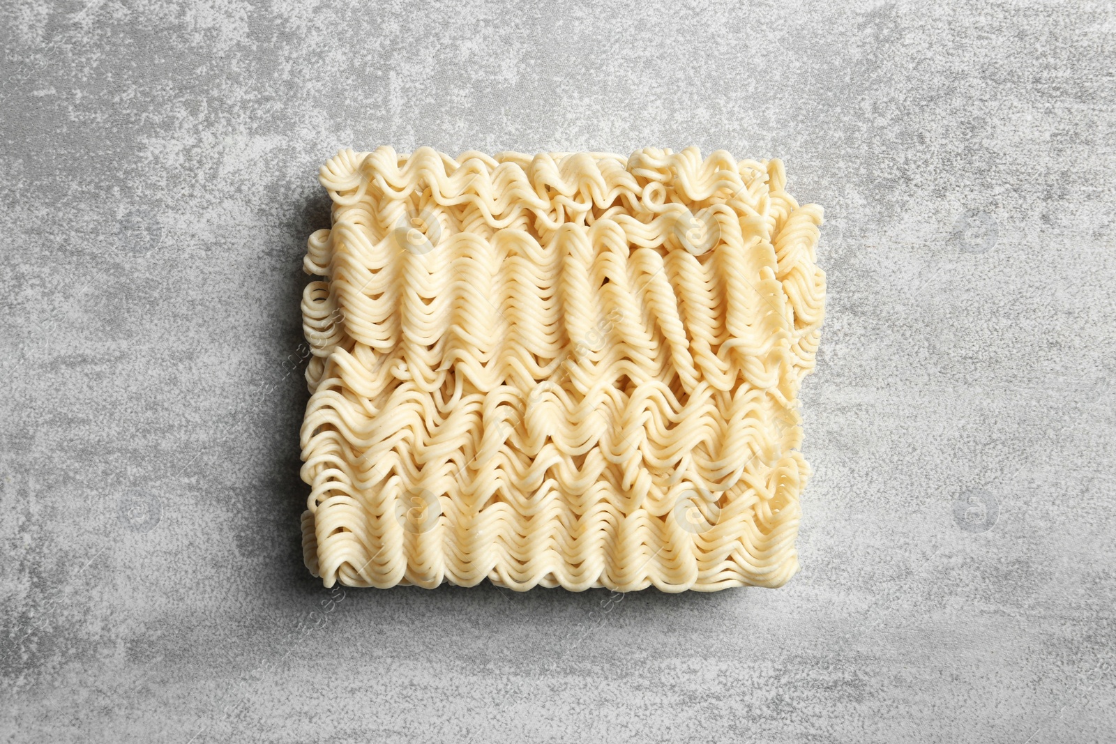 Photo of Block of quick cooking noodles on color background, top view