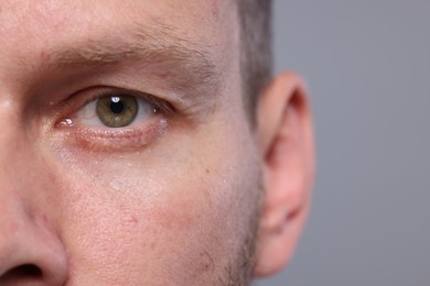 Closeup view of man with beautiful eyes on grey background, space for text