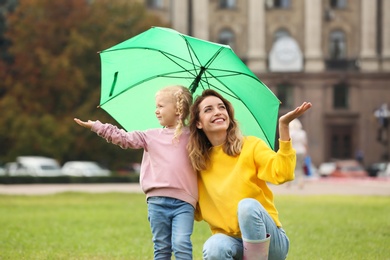 Photo of Happy mother and daughter with umbrella in park