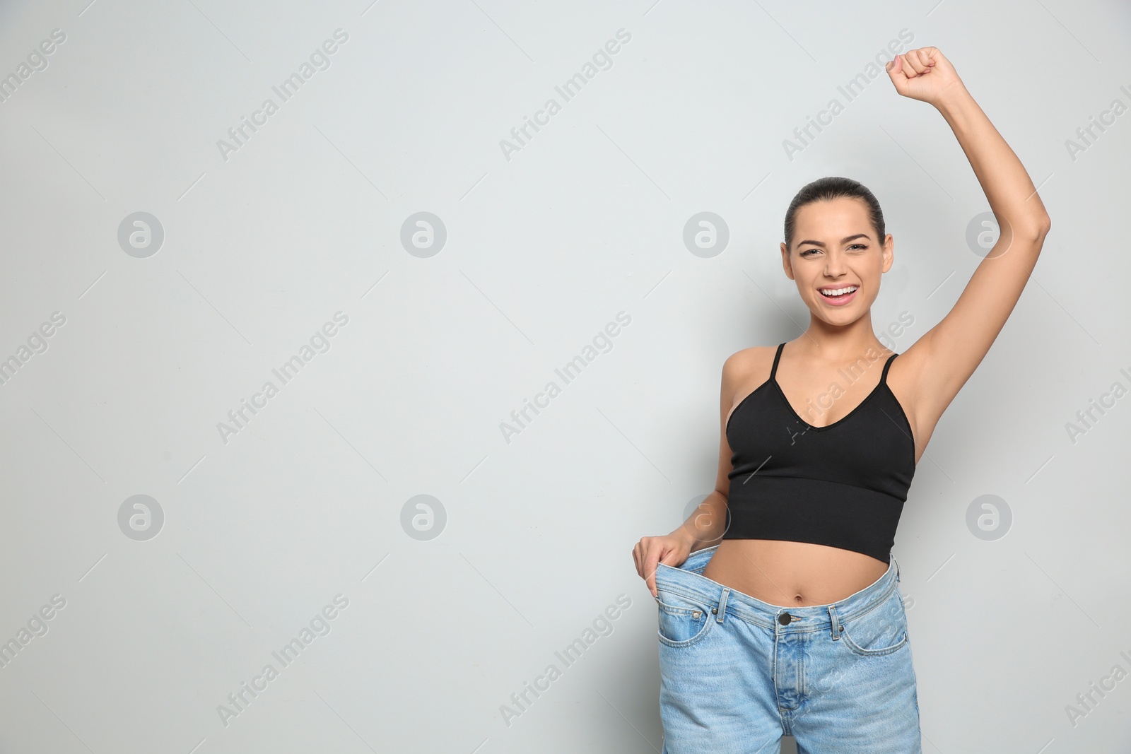 Photo of Slim woman in oversized jeans on light background, space for text. Weight loss