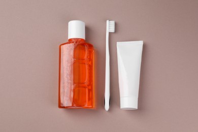 Fresh mouthwash in bottle, toothbrush and toothpaste on beige background, flat lay