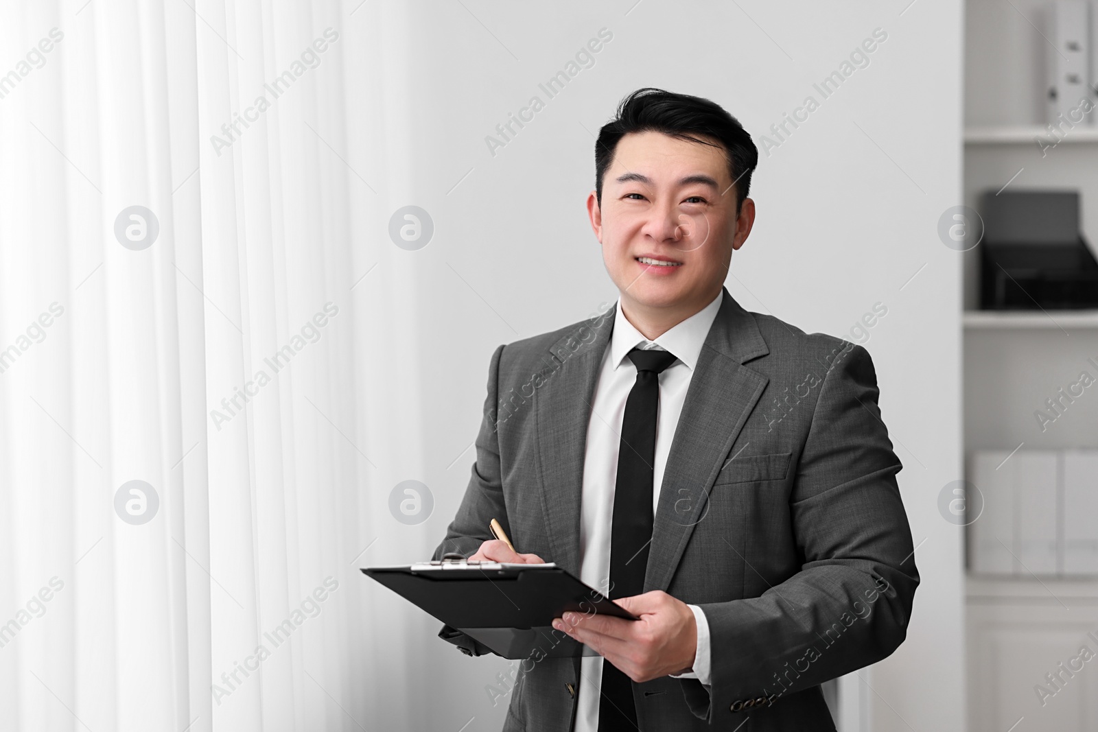 Photo of Portrait of happy notary with clipboard indoors, space for text