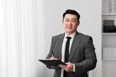 Portrait of happy notary with clipboard indoors, space for text