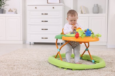 Photo of Cute baby making first steps with toy walker at home, space for text