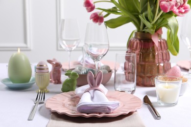 Photo of Festive table setting with napkin ring in shape of bunny ears. Easter celebration