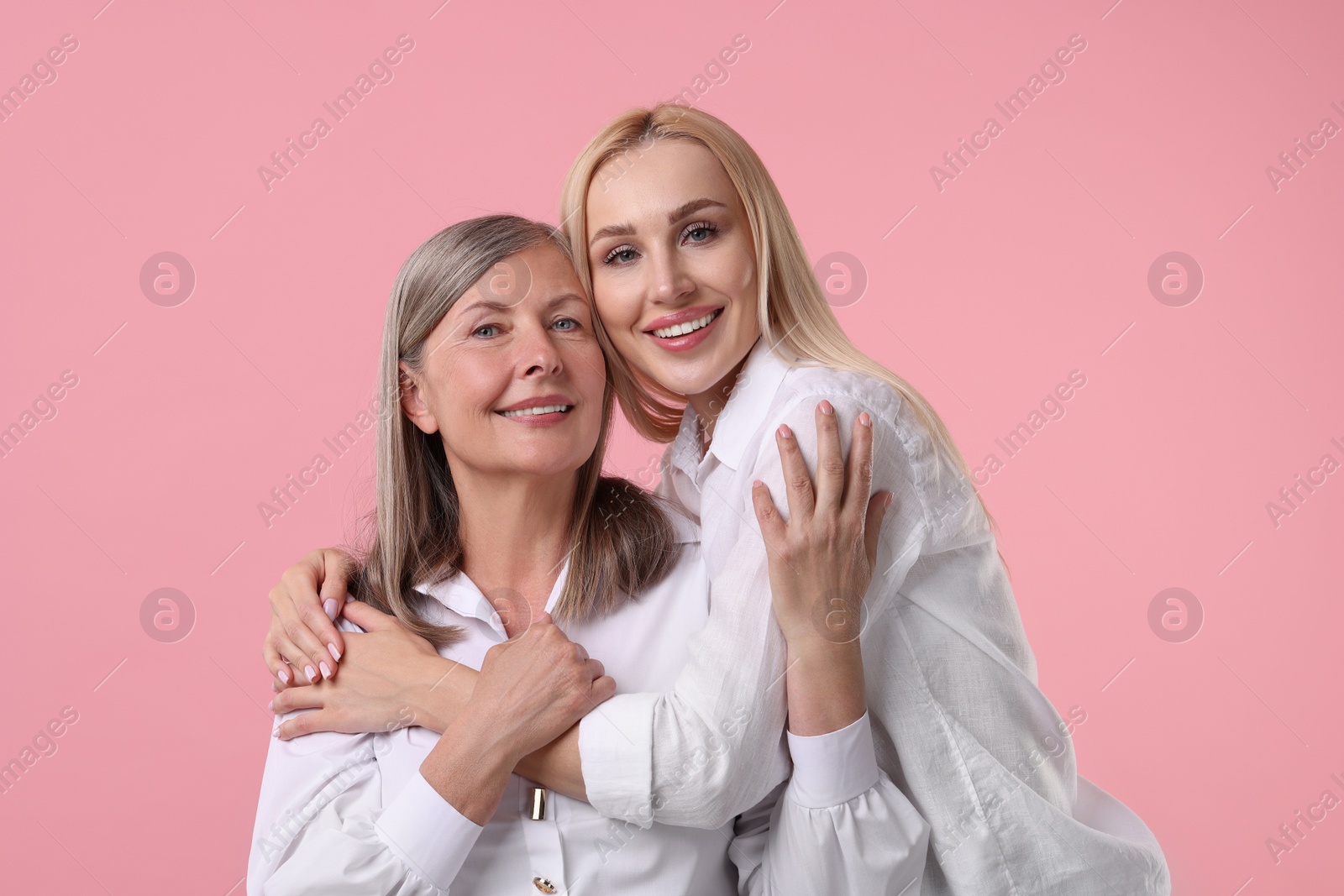 Photo of Family portrait of young woman and her mother on pink background