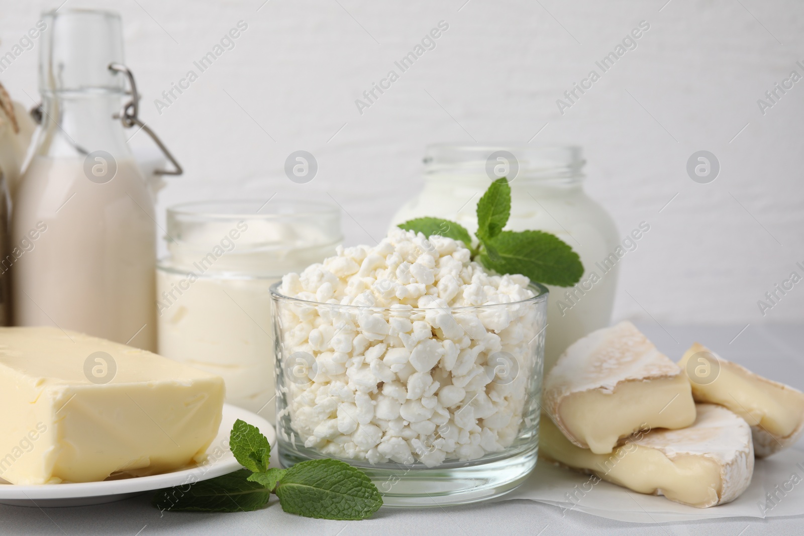 Photo of Different dairy products and mint on white table