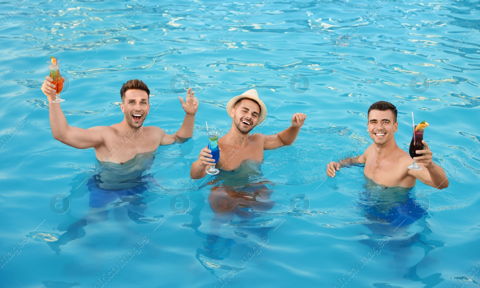 Photo of Happy young friends with refreshing cocktails in swimming pool