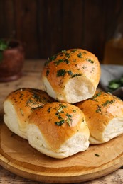 Photo of Traditional pampushka buns with garlic and herbs on wooden table, closeup