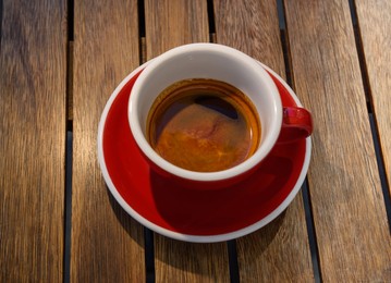 Photo of Cup of aromatic hot coffee on wooden table, above view