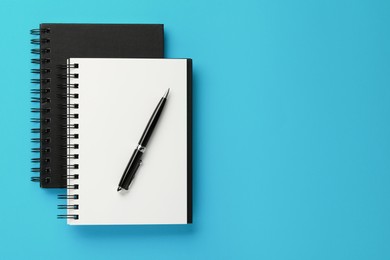 Photo of Notebooks and pen on light blue background, top view. Space for text