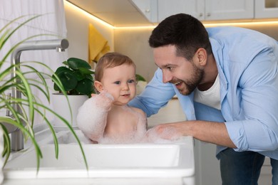 Photo of Father washing his little baby in sink at home