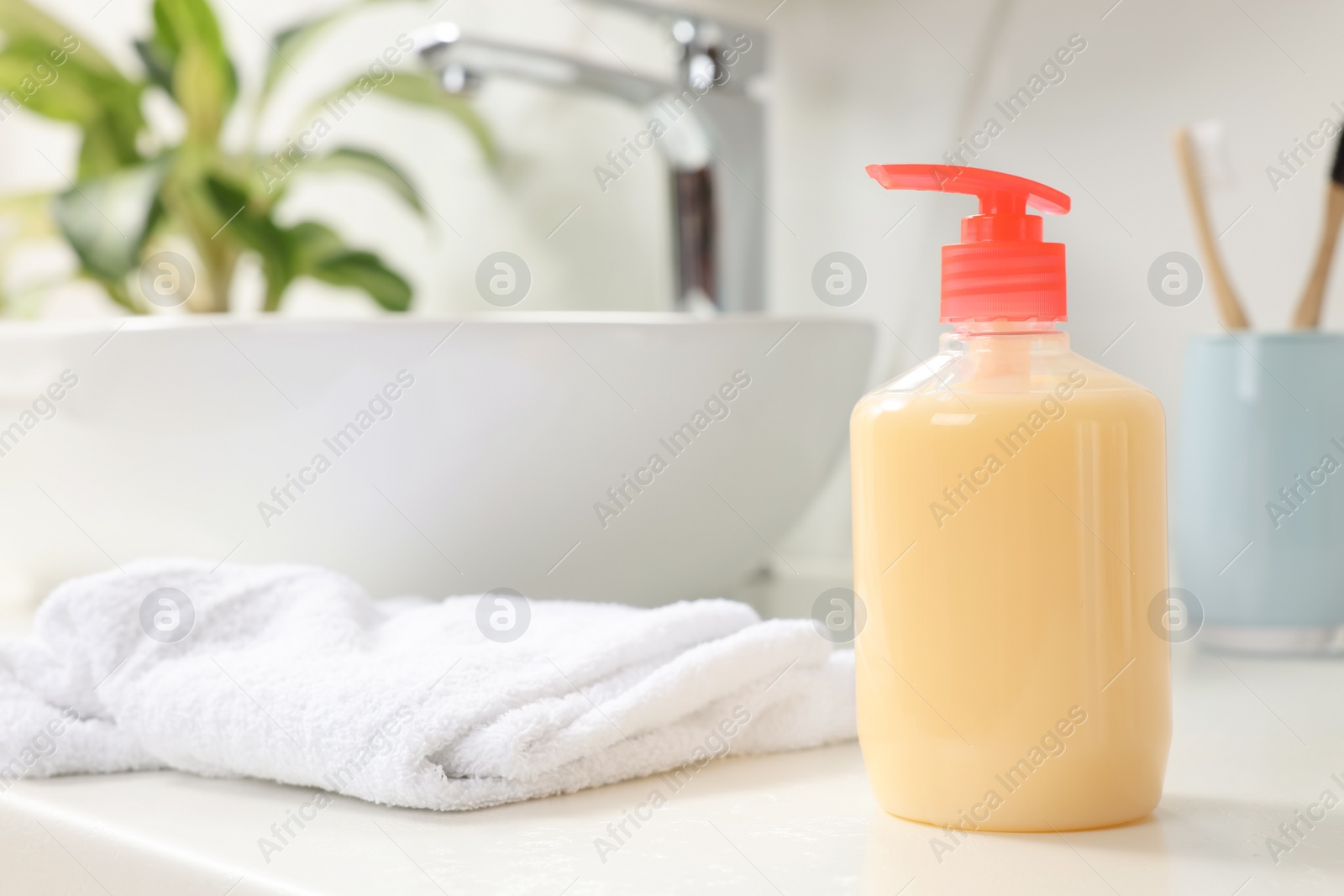 Photo of Dispenser of liquid soap on white table in bathroom, space for text