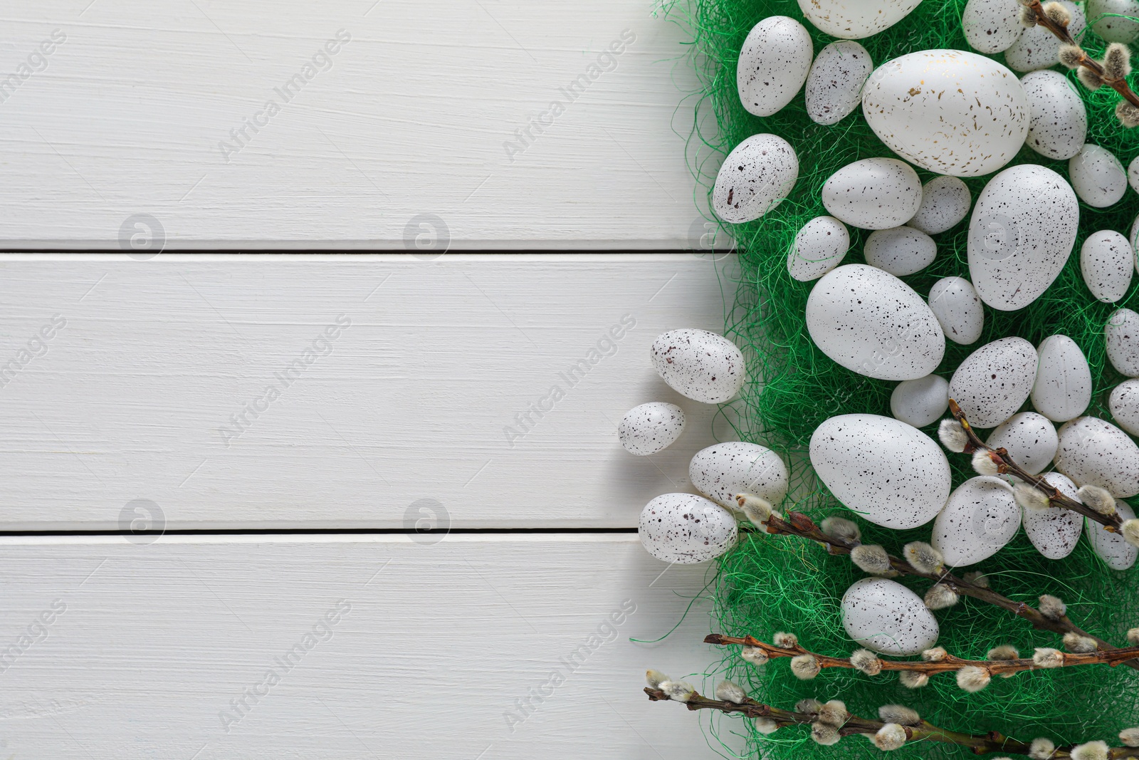 Photo of Many beautifully painted Easter eggs and pussy willow branches on white wooden table, flat lay. Space for text