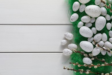 Photo of Many beautifully painted Easter eggs and pussy willow branches on white wooden table, flat lay. Space for text