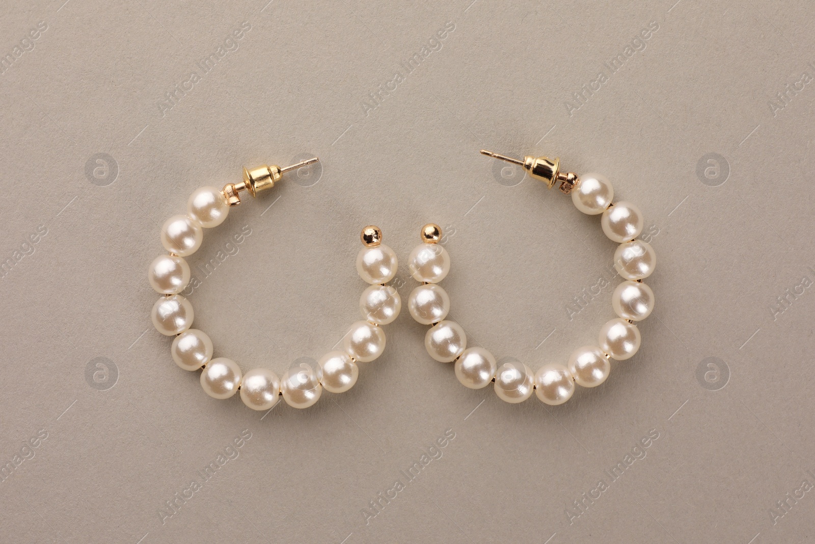 Photo of Elegant earrings with pearls on beige background, top view