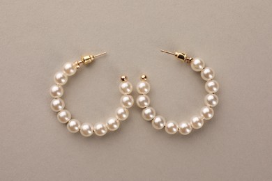 Photo of Elegant earrings with pearls on beige background, top view