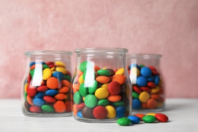 Photo of Jars with small colorful candies on table