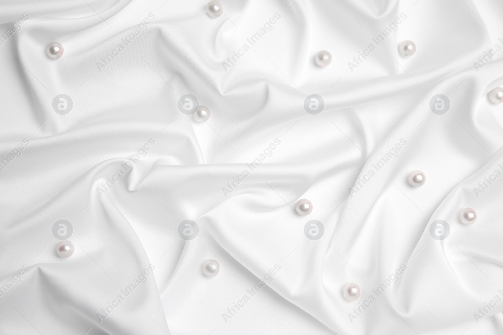 Photo of Beautiful pearls on white silk, flat lay