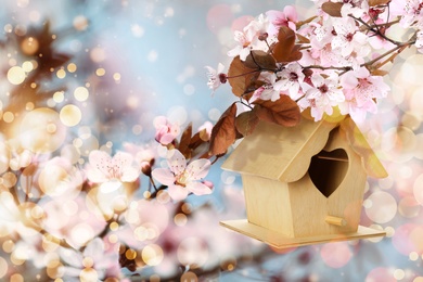 Image of Beautiful wooden bird house hanging on blossoming tree outdoors. Springtime