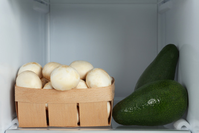 Mushrooms and avocados on shelf in refrigerator